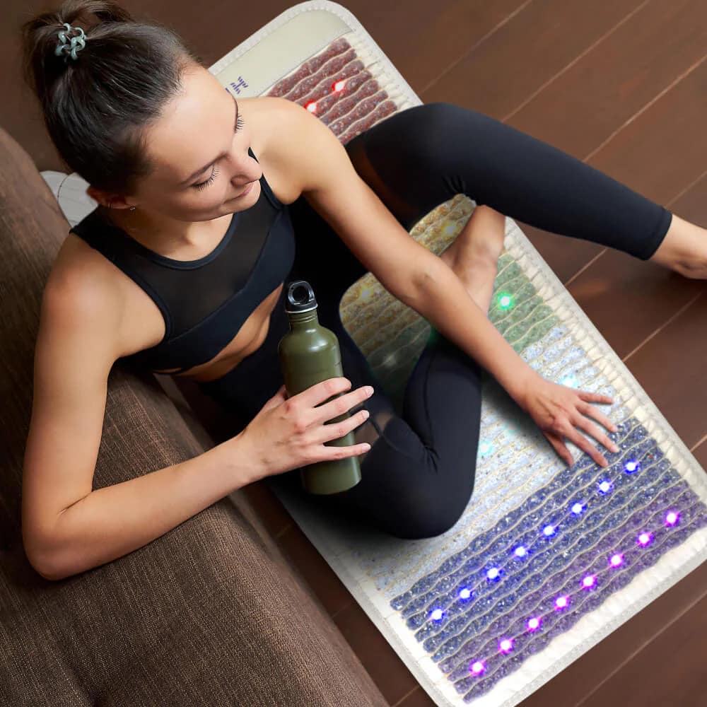 Woman practicing yoga and relaxing on HealthyLine Rainbow Chakra PEMF MiniMat for chakra alignment
