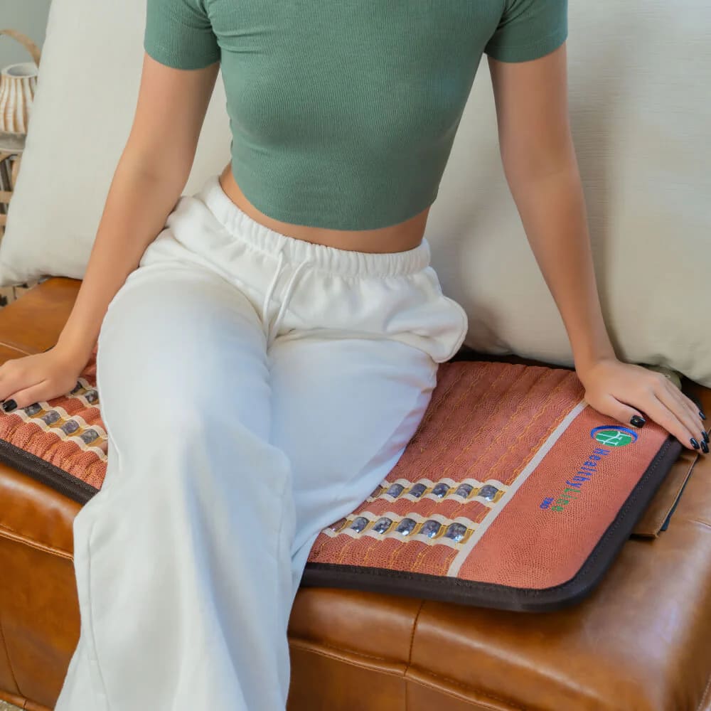 User sitting comfortably on HealthyLine TAO PEMF MiniMat, enjoying portable PEMF benefits
