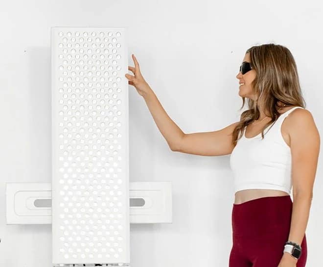 Woman using the side control panel on a wall-mounted MitoPRO 1500+ red light panel