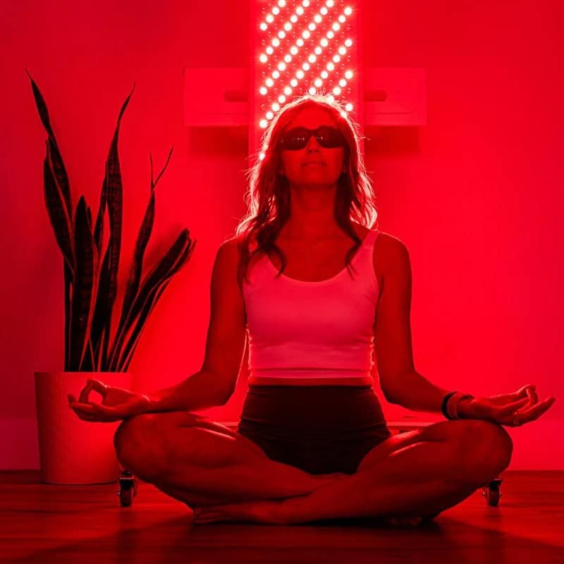 Woman meditating on the floor with her back to the MitoPRO 1500+ mito panel
