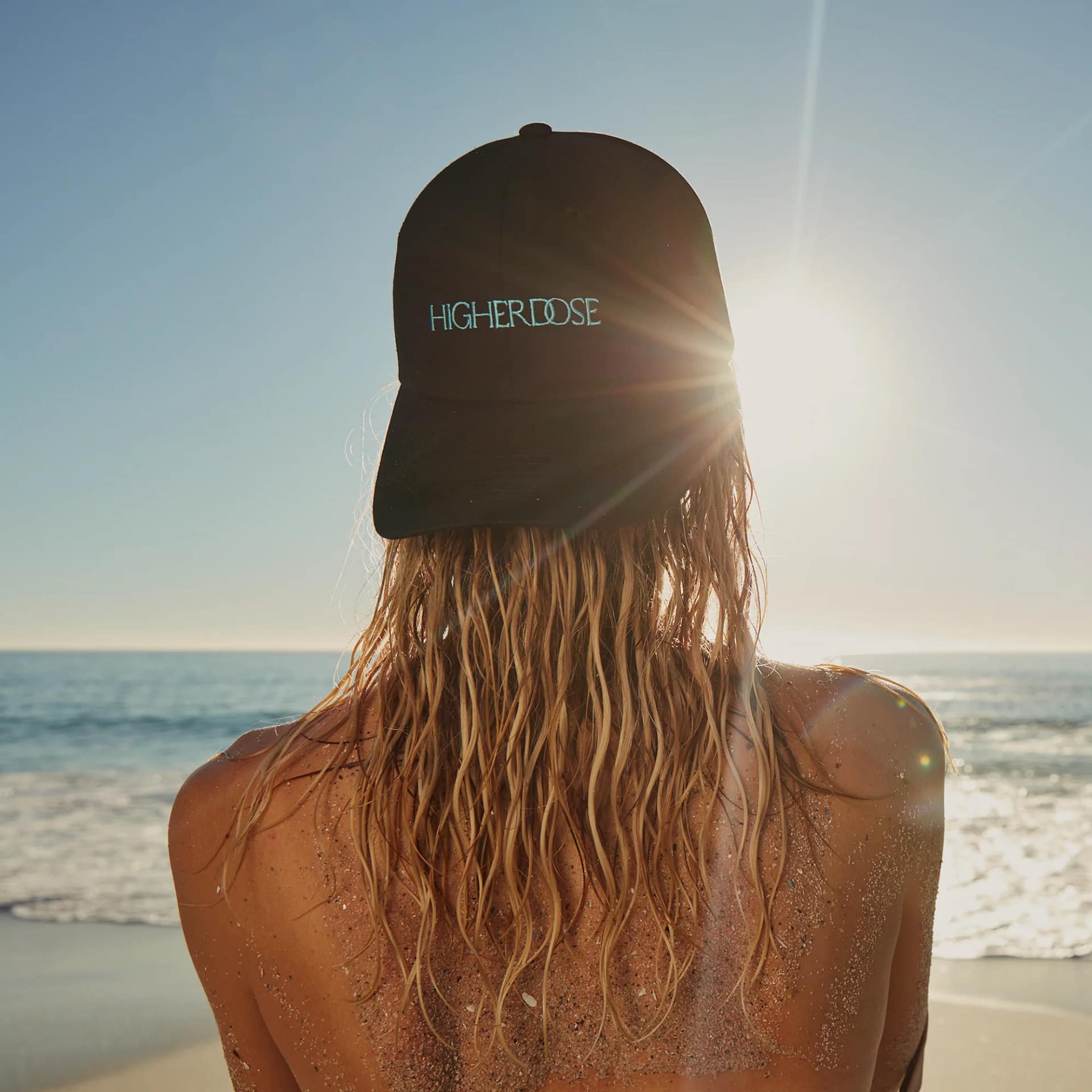 Routine benessere in spiaggia con Cappello LED HigherDose wireless che mostra praticità senza fili
