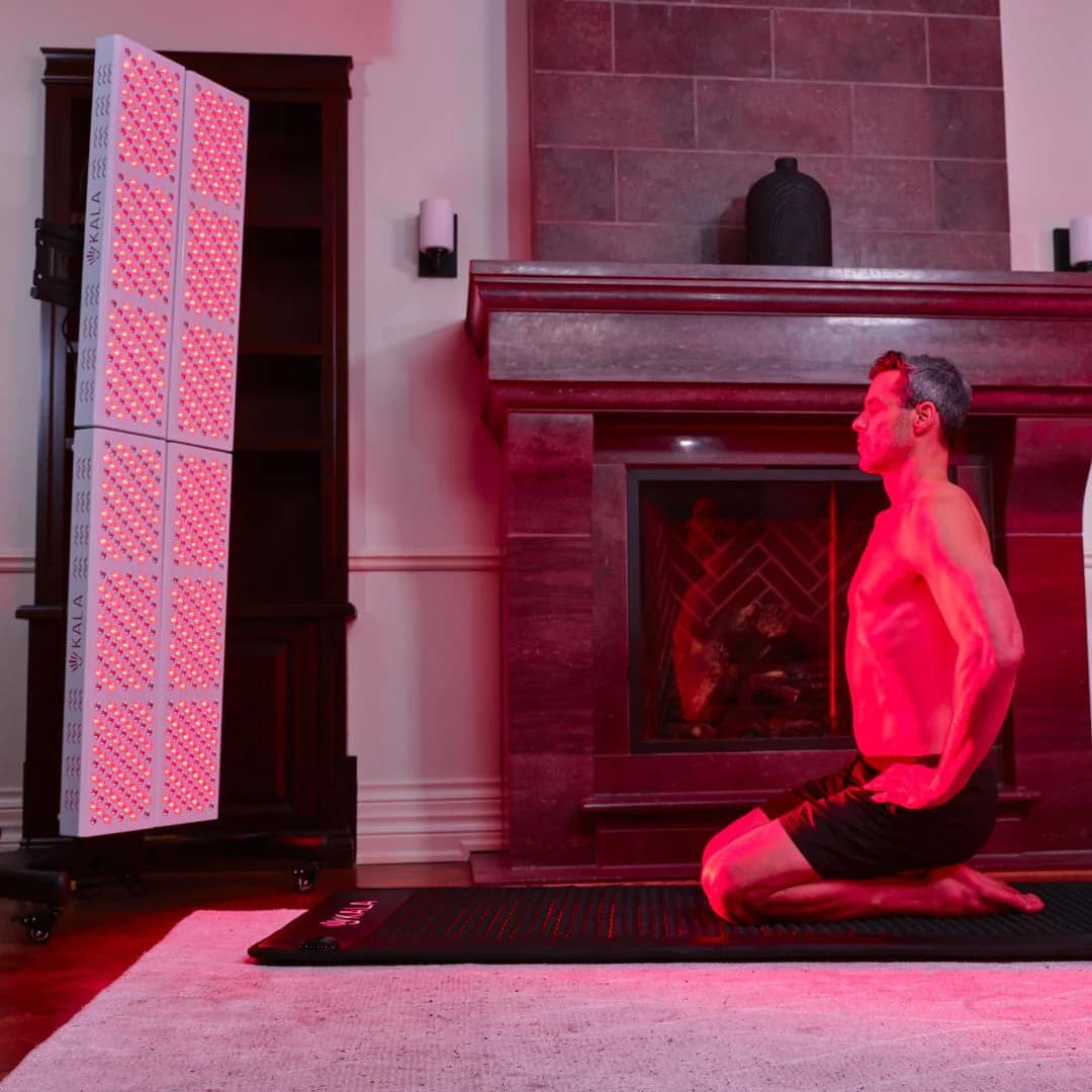 Uomo che medita durante una sessione di terapia a luce rossa con Kala Elite QUAD su supporto verticale