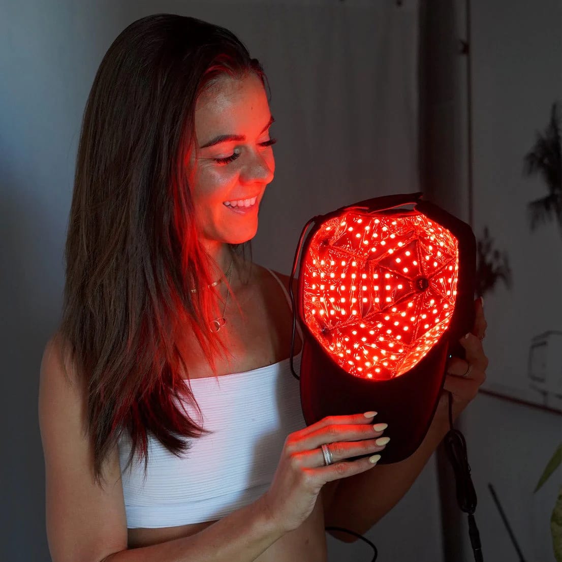 Donna che mostra interno Therasage TheraCap con array LED rossi attivati per terapia cuoio capelluto wireless