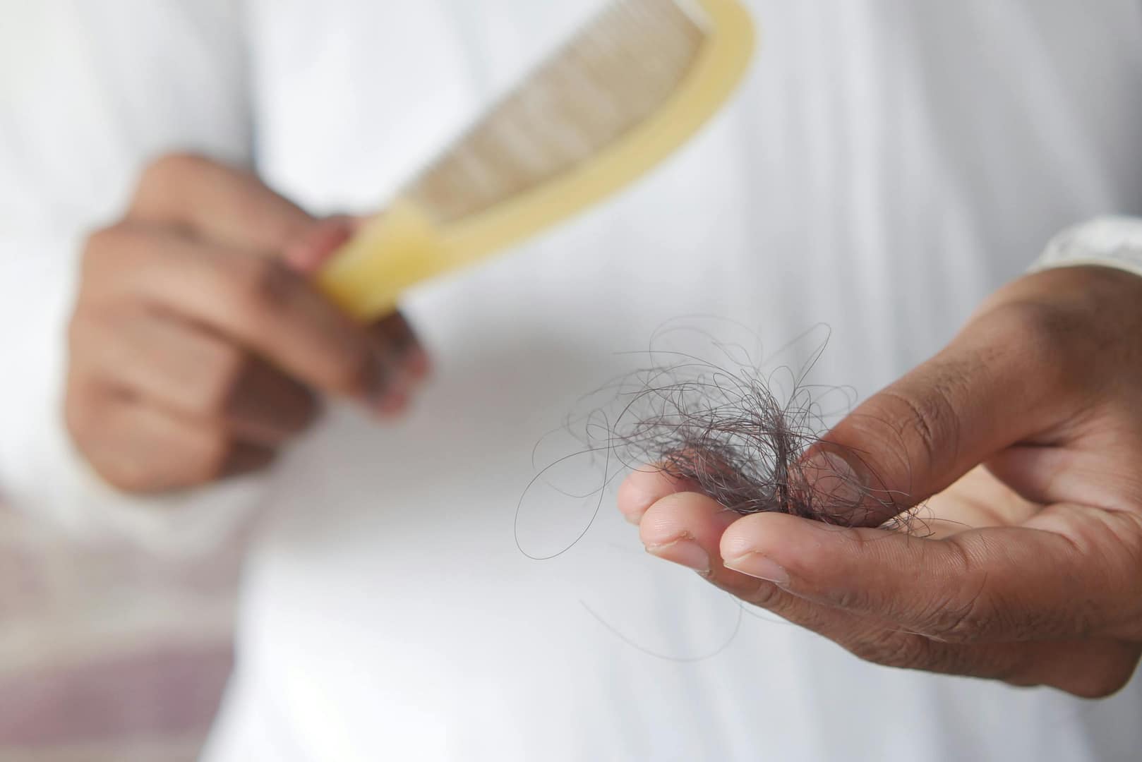 Red Light Therapy for Hair Loss: A detailed image showing hair loss with a comb in hand, symbolizing alopecia and related issues.