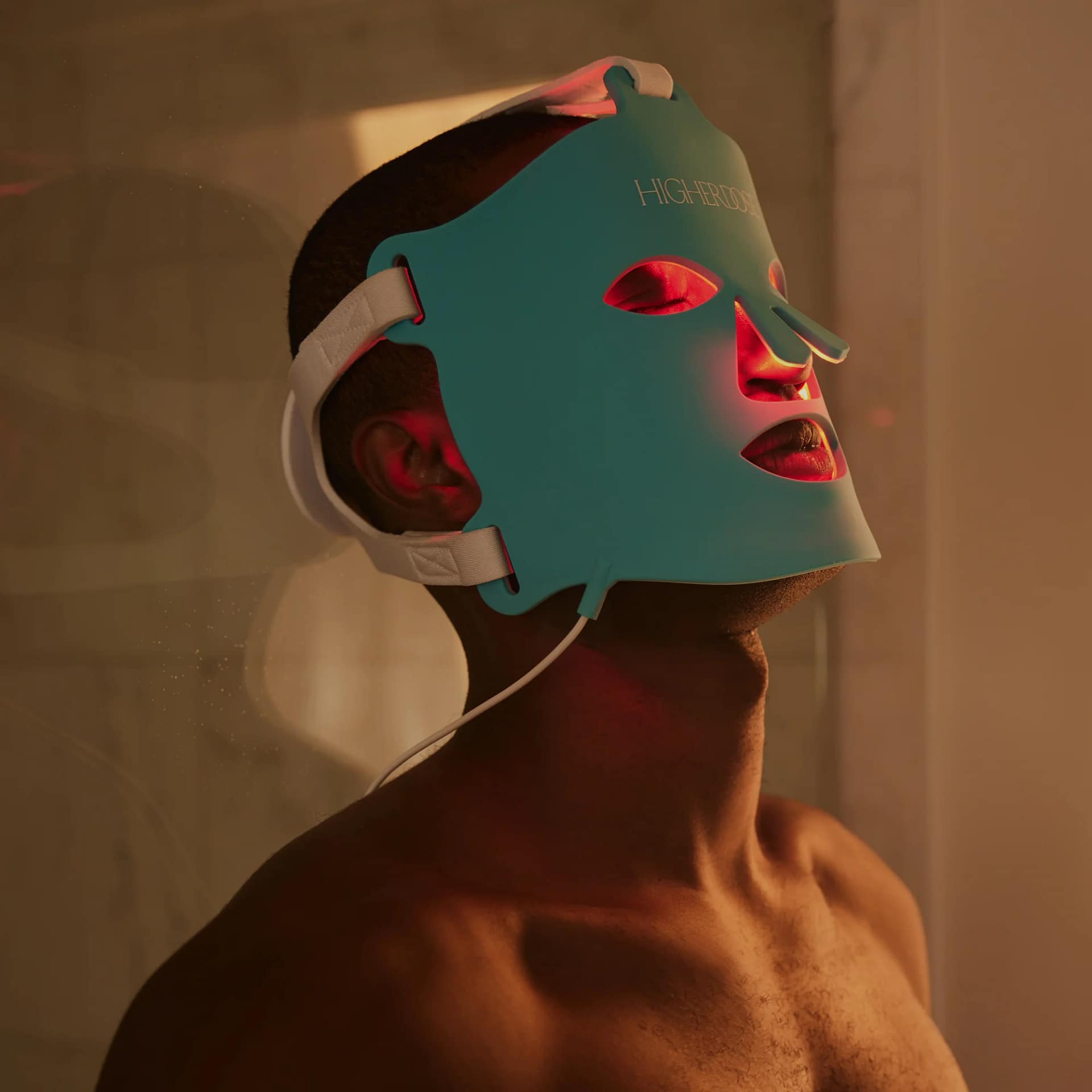 Uomo che usa Maschera Viso LED HigherDose durante sessione terapia a luce rossa a casa