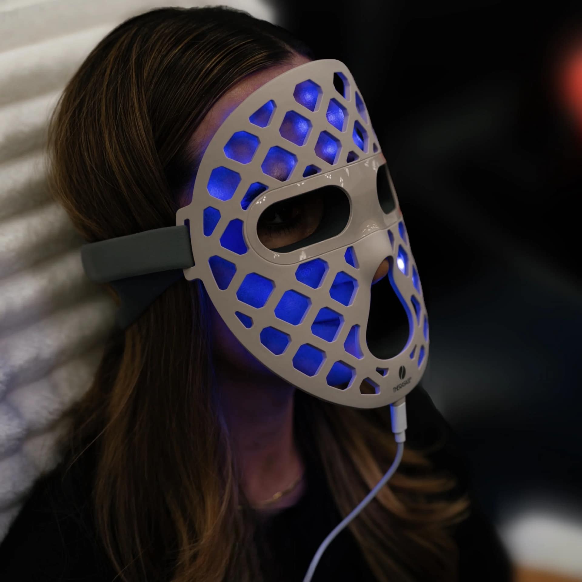 Donna che prova il trattamento a luce blu con Maschera LED Therasage per acne e controllo batterico
