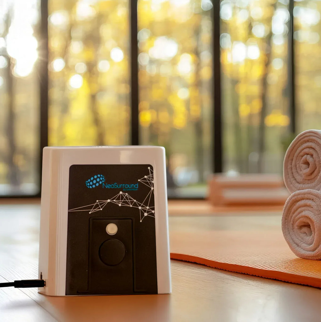 NeoSurround contactless PEMF device on the floor in a yoga studio next to rolled yoga mats