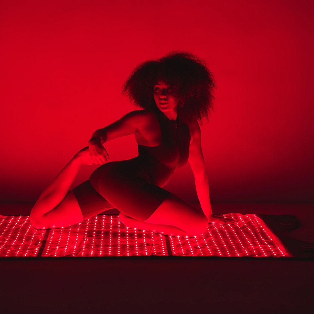 Woman practicing yoga on HigherDose Red Light Therapy Mat for combined exercise and LED treatment session