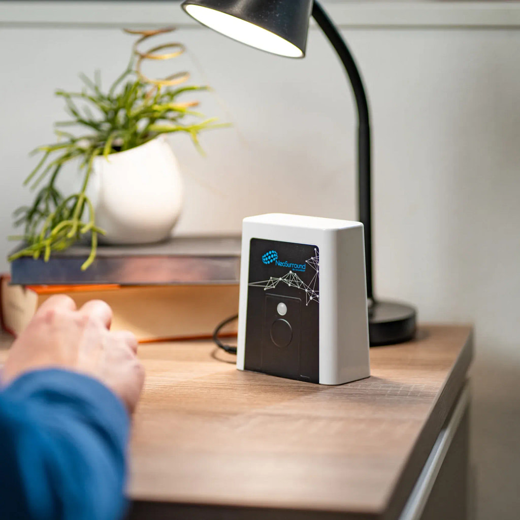 NeoSurround PEMF review, device on a desk next to a person working on a laptop