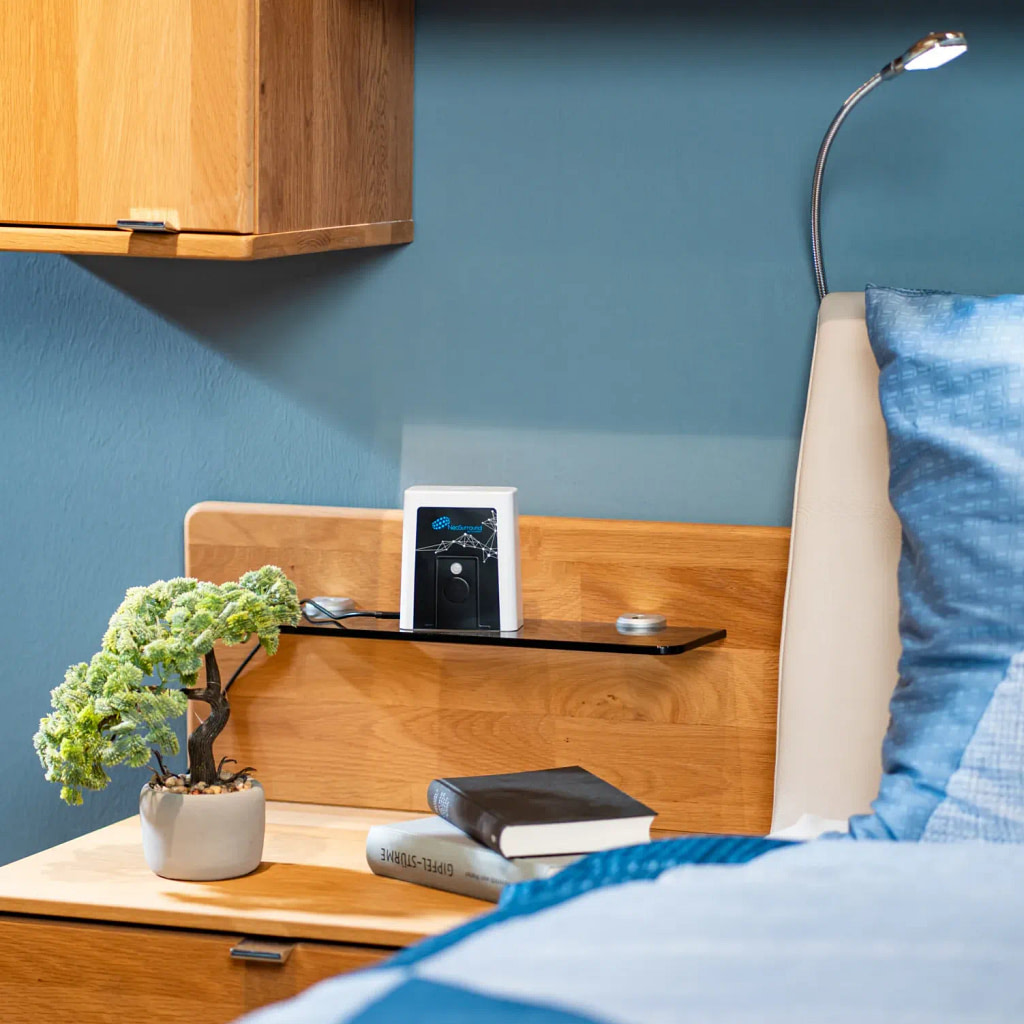 OmniPEMF NeoSurround PEMF system on a small shelf next to a bed