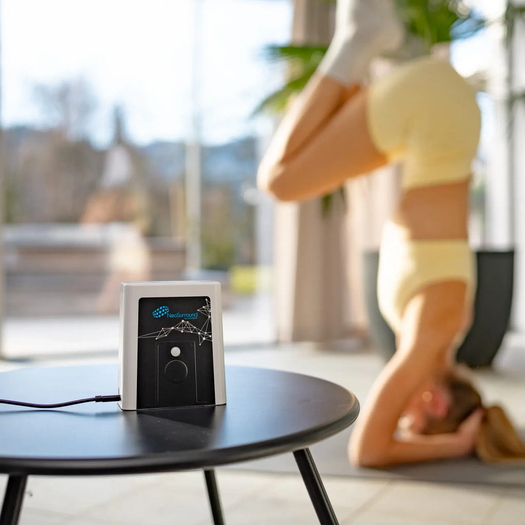 OmniPEMF NeoSurround PEMF system running while a woman practices yoga nearby