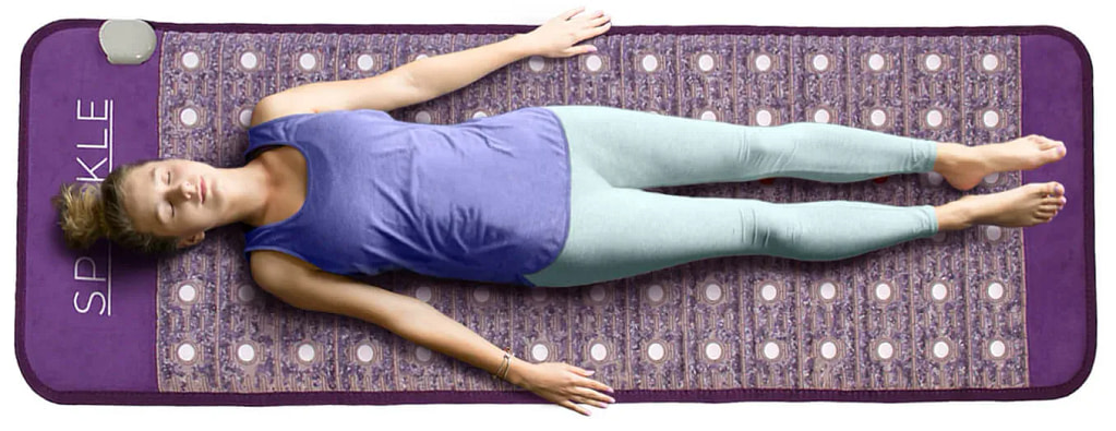 Overhead view of woman relaxing on Sparkle PEMF mat during risk‑free trial