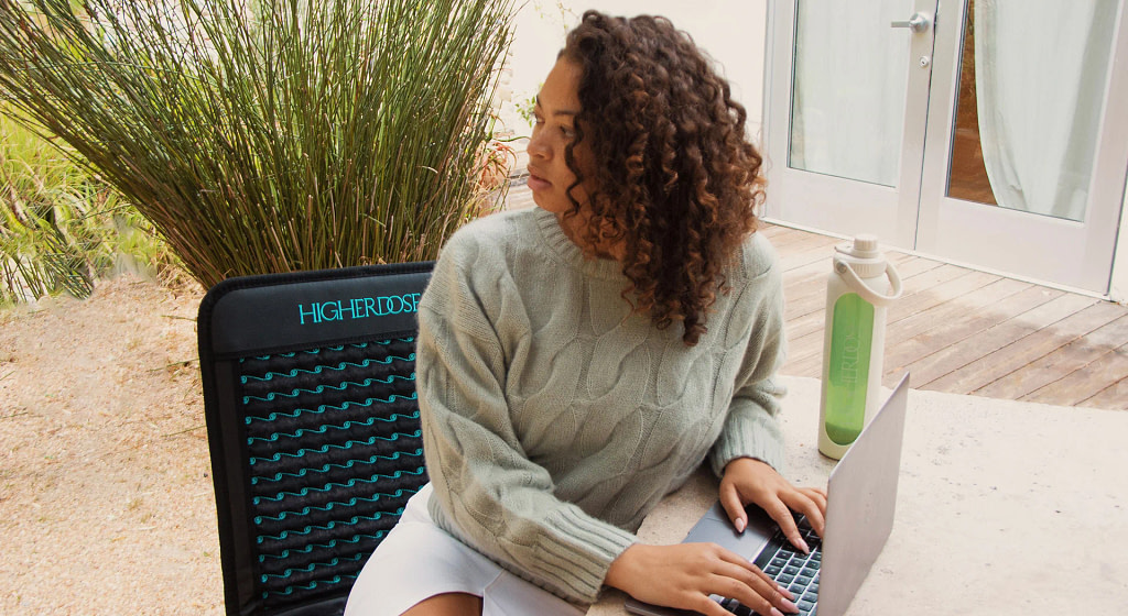 Portable PEMF therapy mat woman working at computer demonstrating office wellness setup