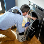 Man loading the washing machine wearing the Celler8 unit on his shoulder-back
