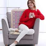 Woman enjoying coffee while using HealthyLine TAJ Chair PEMF Mat for back pain relief