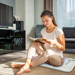 Woman relaxing and reading on HealthyLine Platinum PEMF MiniMat for premium therapy