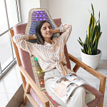 Young woman enjoying chakra balancing benefits on HealthyLine Rainbow Chakra PEMF Chair Mat
