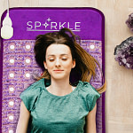 Woman unwinding on the Sparkle PEMF mat with negative ion and FIR benefits