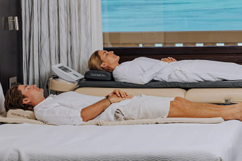 Two individuals using Sedona Pro PEMF Mats simultaneously for wellness therapy
