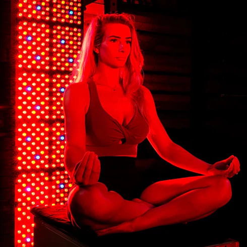 Relaxing meditation near red light therapy panel for stress relief