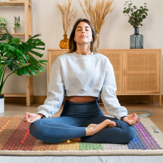 Seated meditation on the HealthyLine Rainbow Chakra PEMF Mat for spiritual healing