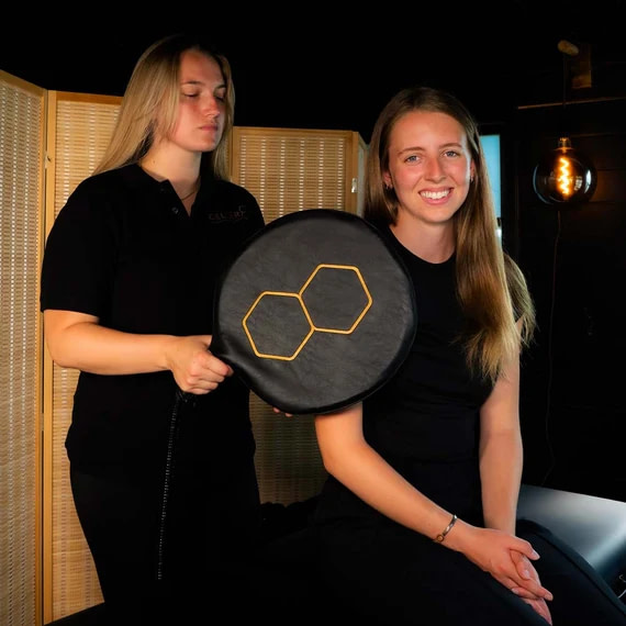 Practitioner holding the Celler8 MAX pad applicator against a client's shoulder