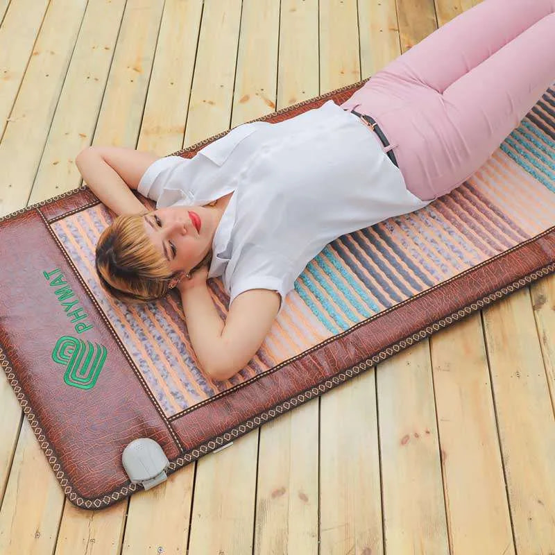 Woman lying relaxed on Phymat Gemstones PEMF mat for therapy and chakra support