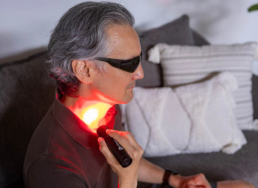 Man treating neck area with LifePro LED Torch for targeted pain relief and muscle relaxation therapy