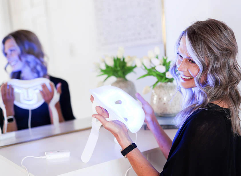 Woman examining LifePro RevitaGlow Face Mask before LED therapy session