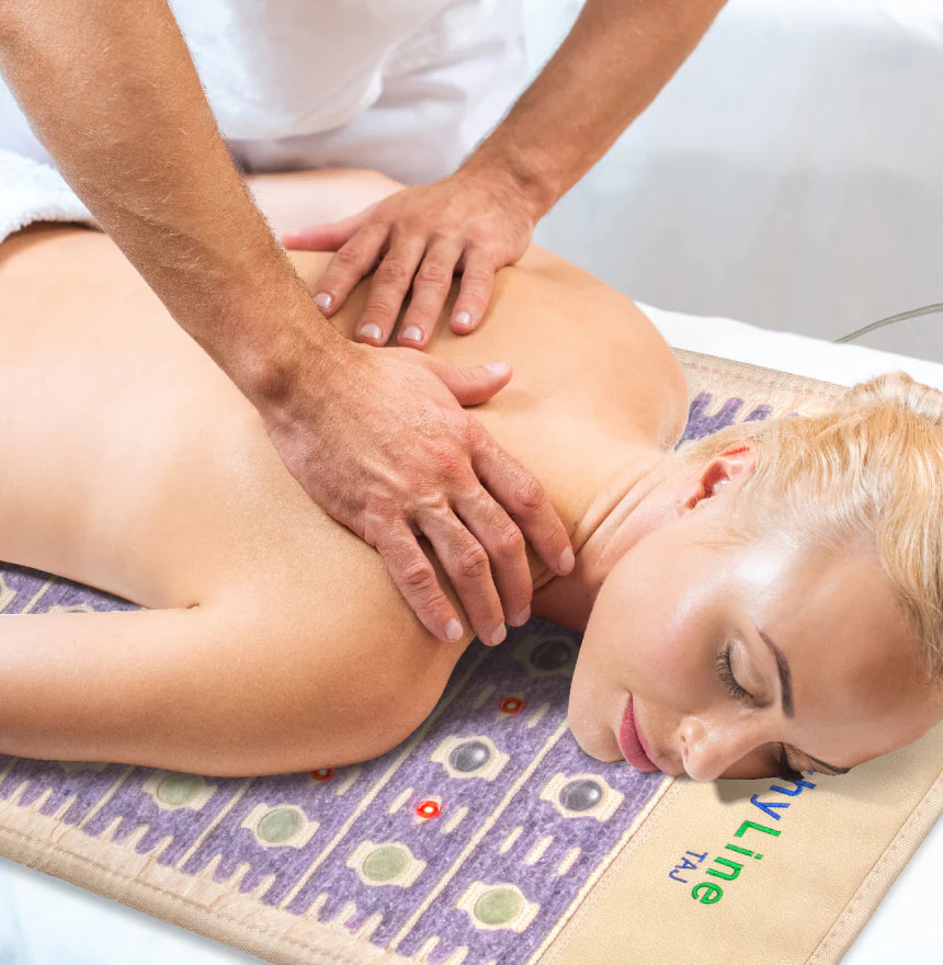 Woman receiving back massage while lying on HealthyLine TAJ PEMF Mat for muscle relaxation