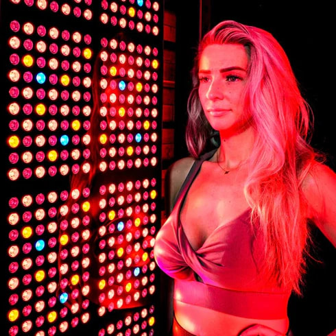 Woman with full body red light therapy panel for wellness benefits