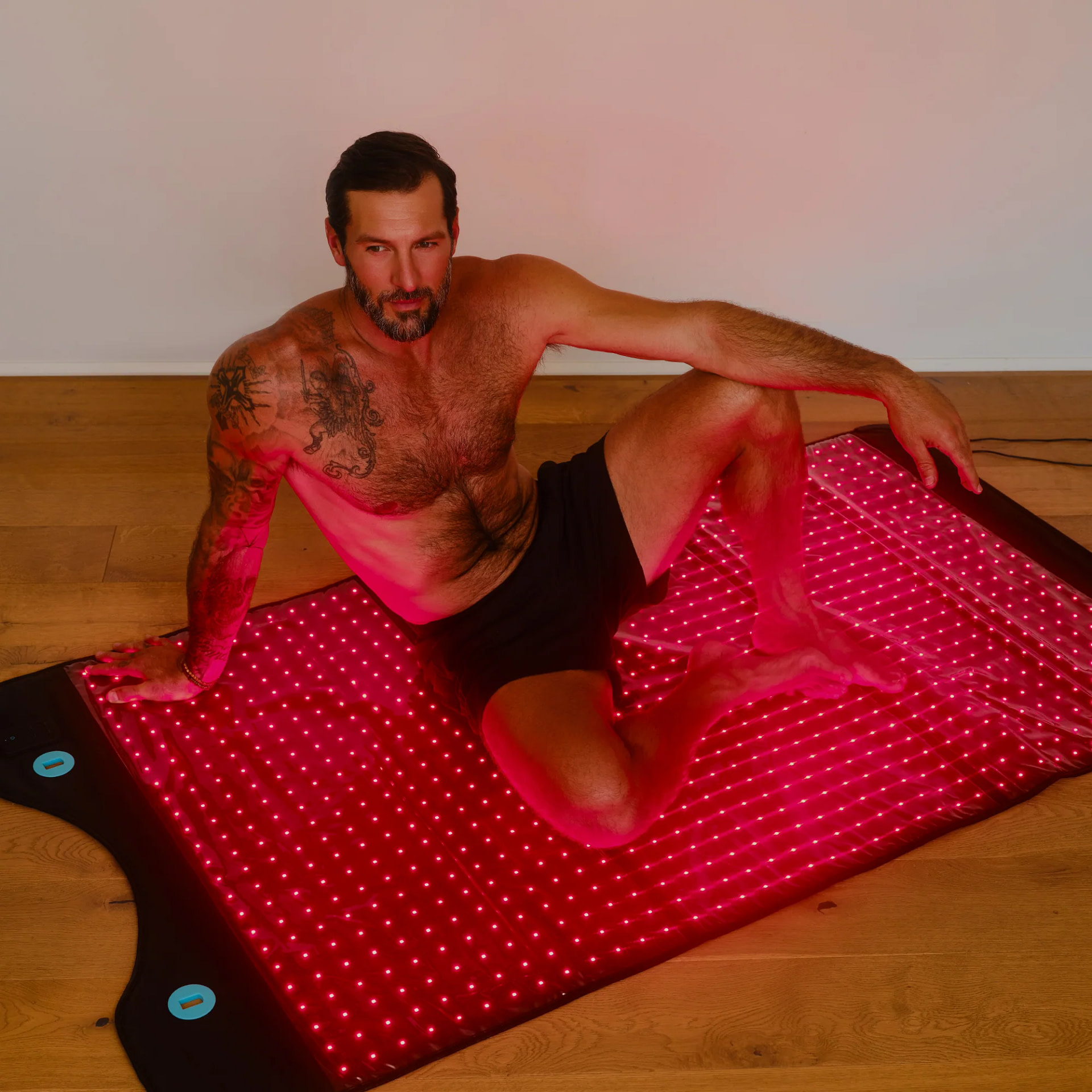 Man relaxing on HigherDose Red Light Mat during floor-based full-body LED therapy session