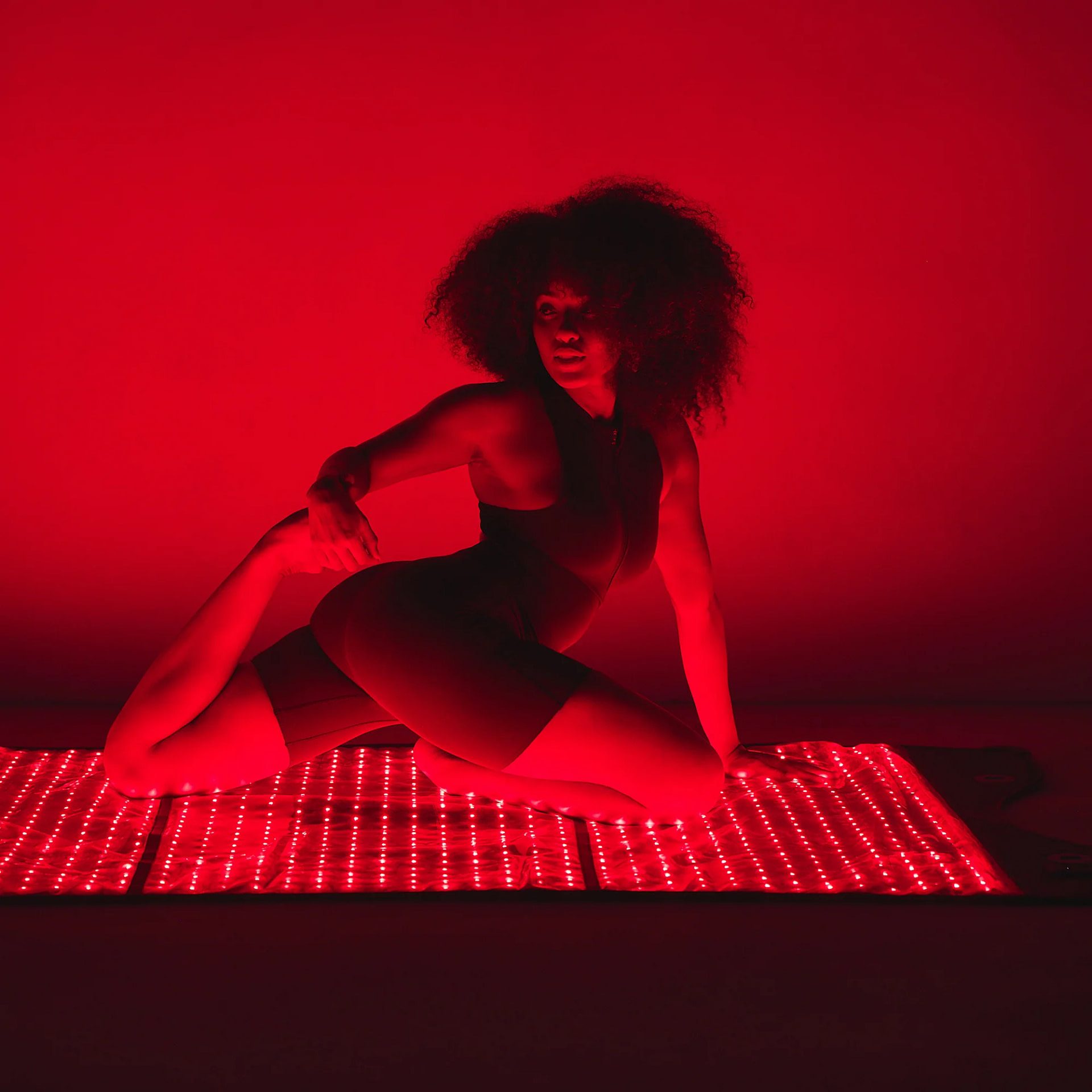Woman practicing yoga on HigherDose Red Light Therapy Mat for combined exercise and LED treatment session