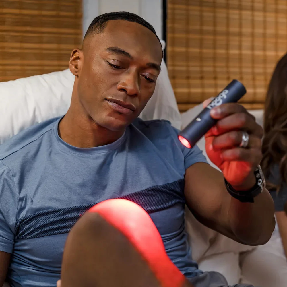 Man treating knee joint with Hooga LED Torch for targeted pain relief and recovery therapy at home