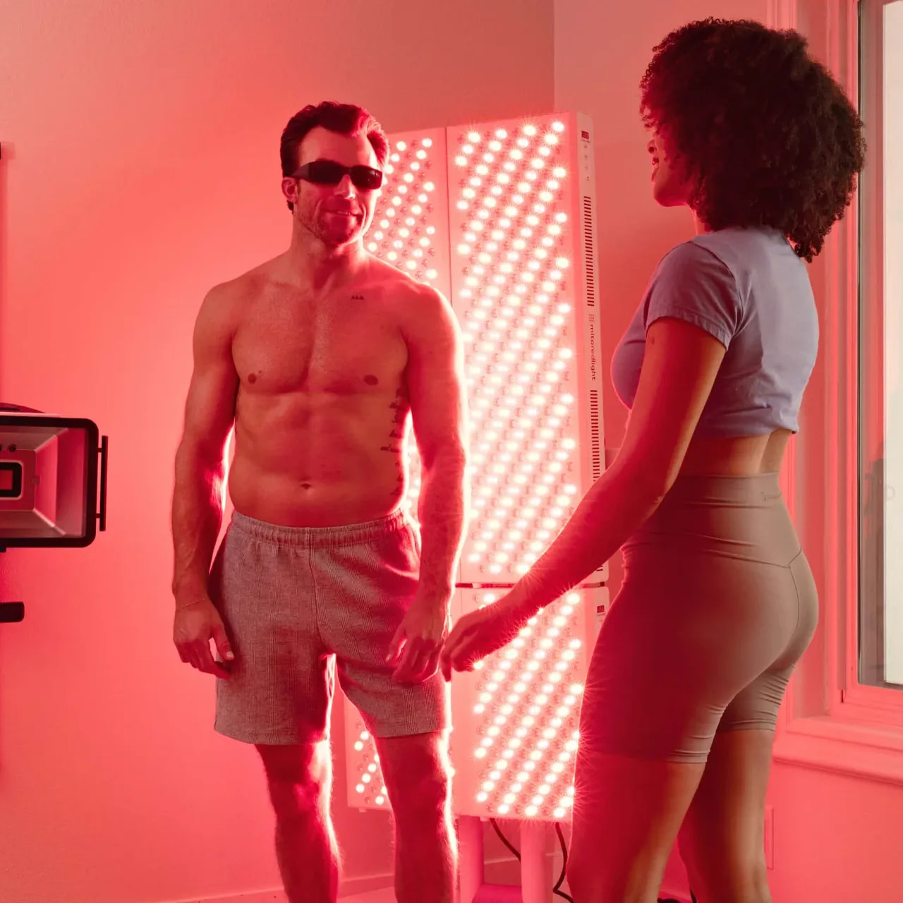 A man and woman talking in a room lit by a MitoPRO 1500+ Mito red light panel
