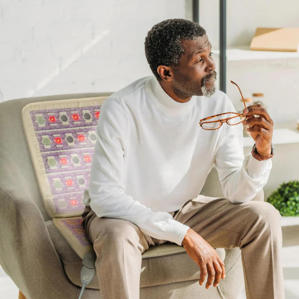 Man relaxing on HealthyLine TAJ Chair PEMF Mat, gazing out the window during therapy