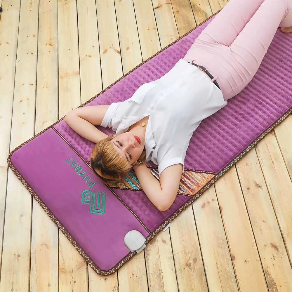Woman lying relaxed on Phymat Amethyst PEMF Mat for full body PEMF and infrared therapy