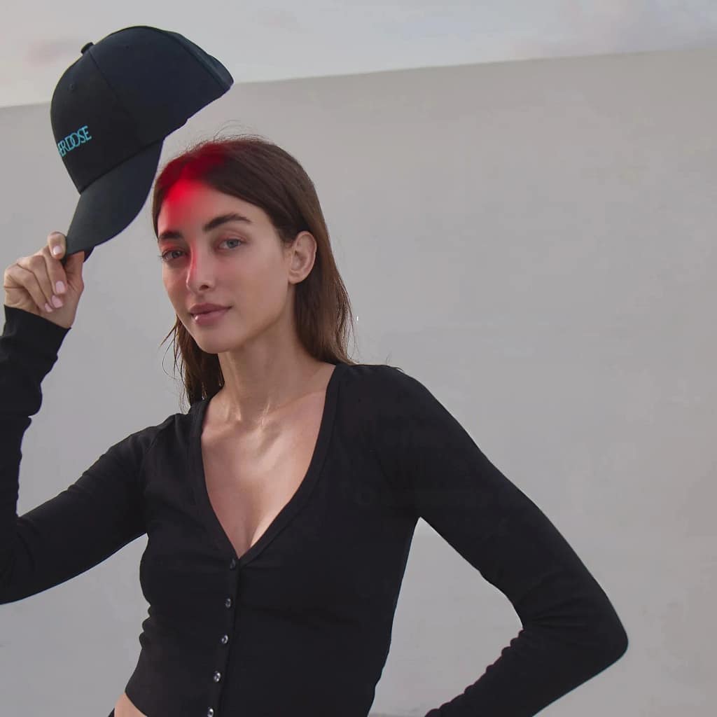 Woman displaying HigherDose LED Hat activated in wireless mode for portable scalp treatment