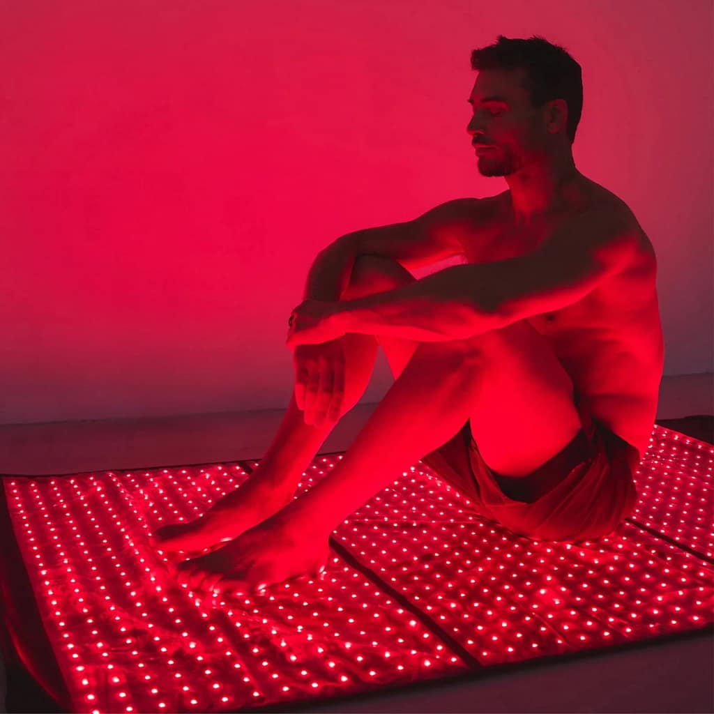 Man seated on HigherDose Red Light Therapy Mat for targeted lower body and back LED treatment