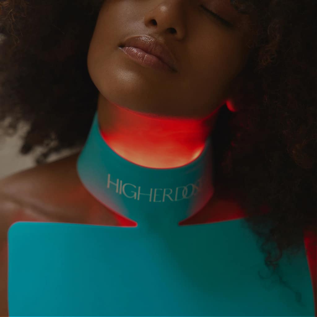 HigherDose Red Light Neck Enhancer activated showing illuminated LED array for décolletage rejuvenation treatment