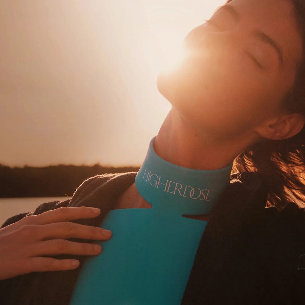 Woman using HigherDose Red Light Therapy Neck Enhancer outdoors demonstrating lifestyle-friendly LED treatment