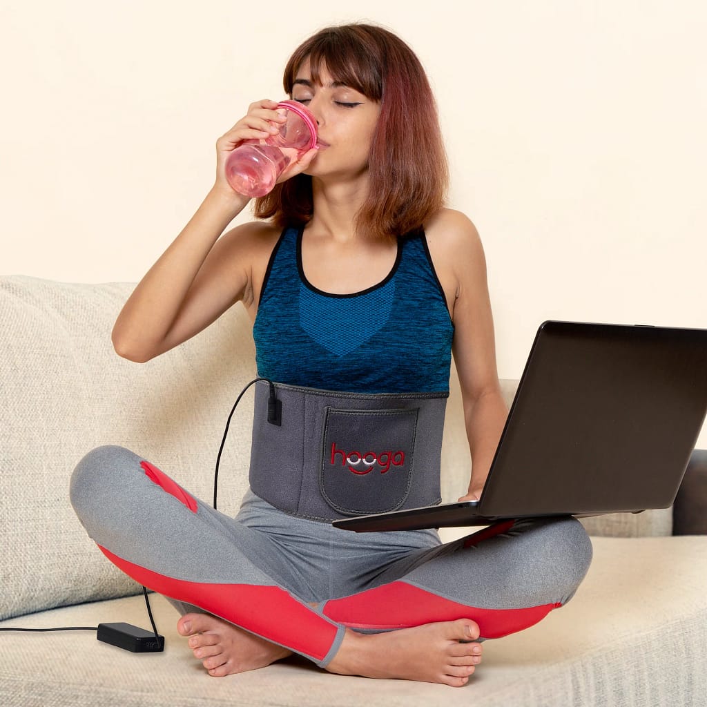 Woman multitasking with Hooga Red Light Belt during hands-free therapy session at home