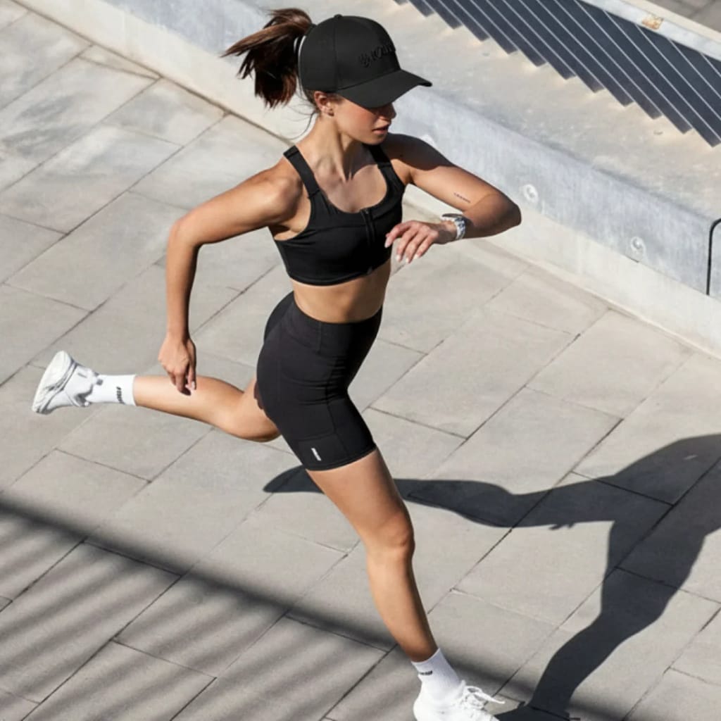 Woman running outdoors while wearing Kala LED Hat demonstrating battery-powered portability and active use