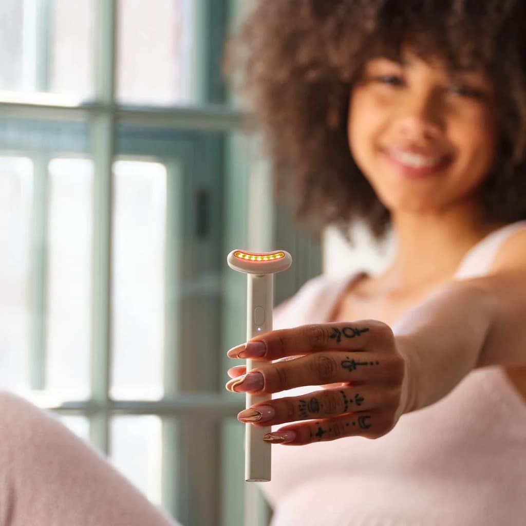 Woman displaying Kala Red Light Therapy Wand handheld portable LED facial treatment tool