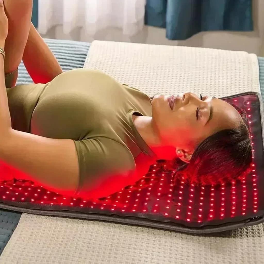 Woman performing floor exercises on LifePro AllevaBody Red Light Mat for active recovery therapy