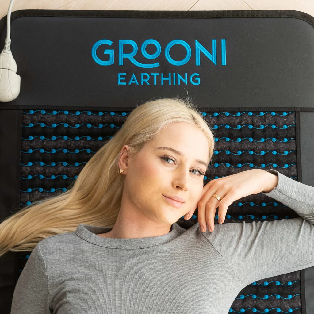 User experiencing stress relief on Grooni PEMF mat with infrared heat