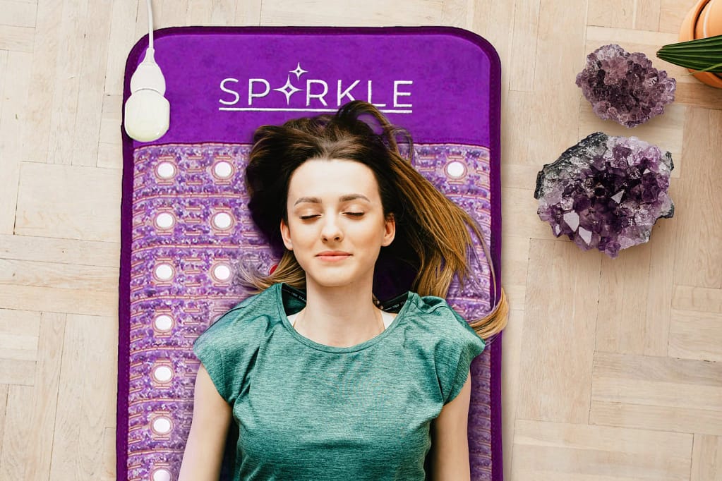Woman unwinding on the Sparkle PEMF mat with negative ion and FIR benefits