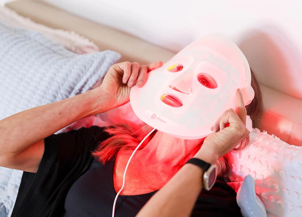 Woman using LifePro RevitaGlow Red Light Therapy Mask for anti-aging treatment