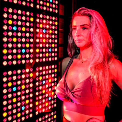 Woman with full body red light therapy panel for wellness benefits