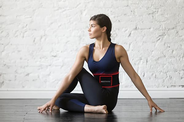 Woman combining BestQool LED Belt therapy with home yoga practice for wellness and recovery